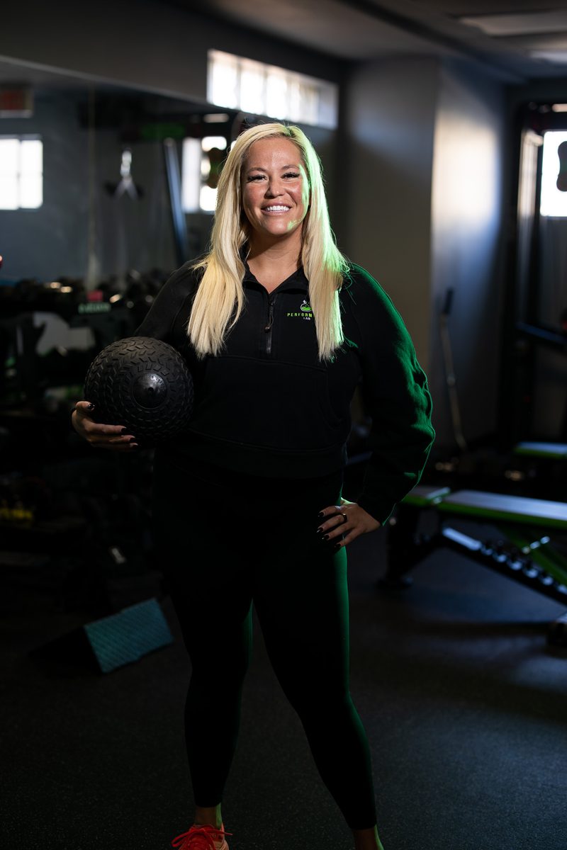 Environmental fitness portrait of a blonde woman with dumbbells in a gym