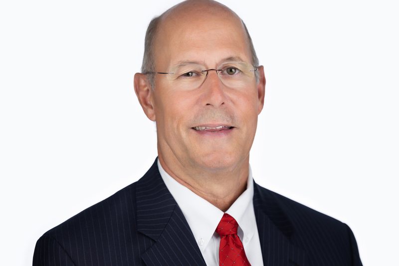 Corporate headshot of a businessman in a red tie on a white background