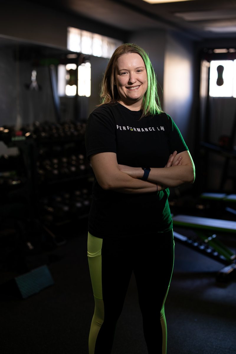 Environmental portrait of a female trainer with arms crossed in a gym